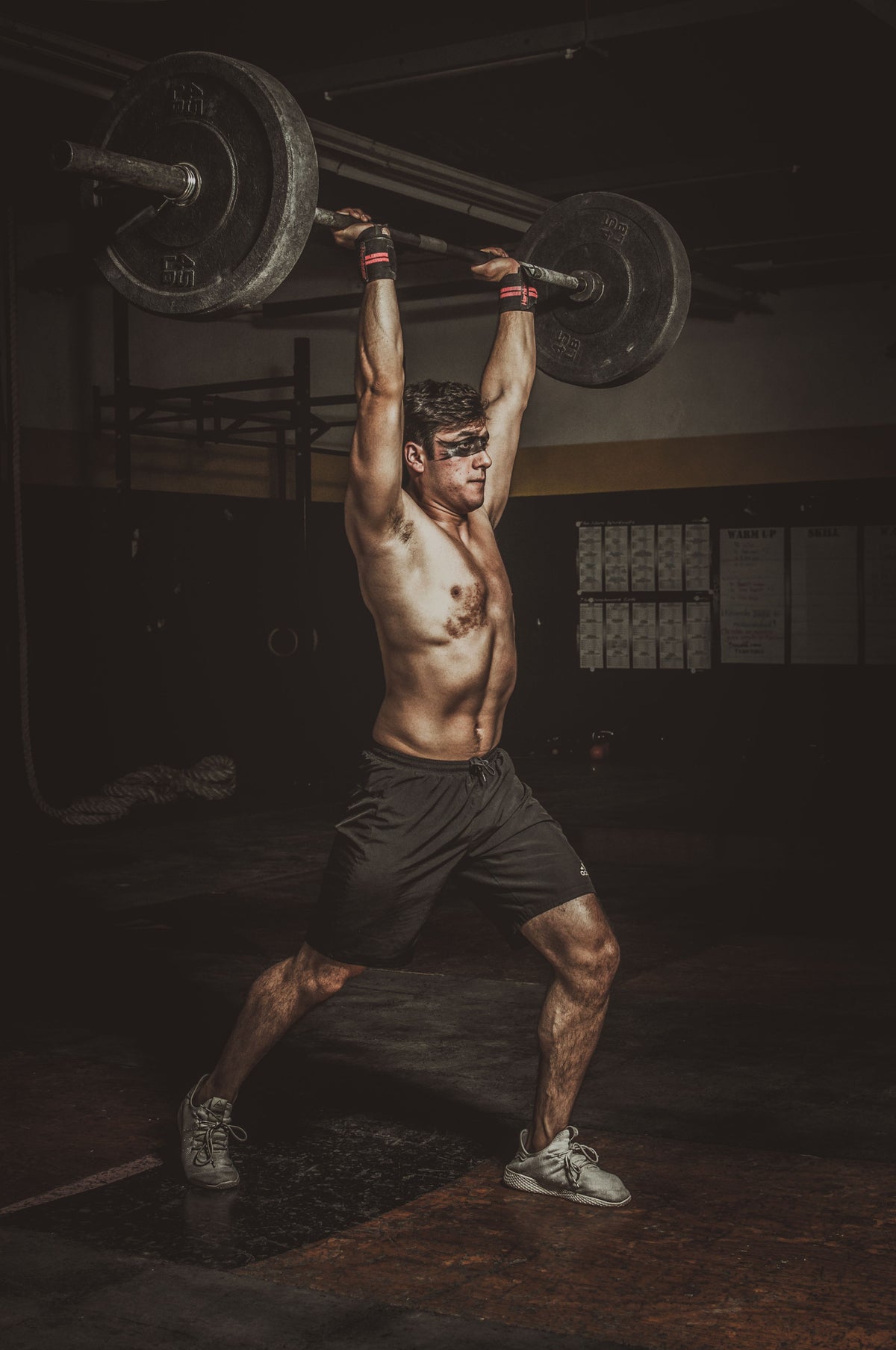 Man lifting a barbell in a dimly lit gym