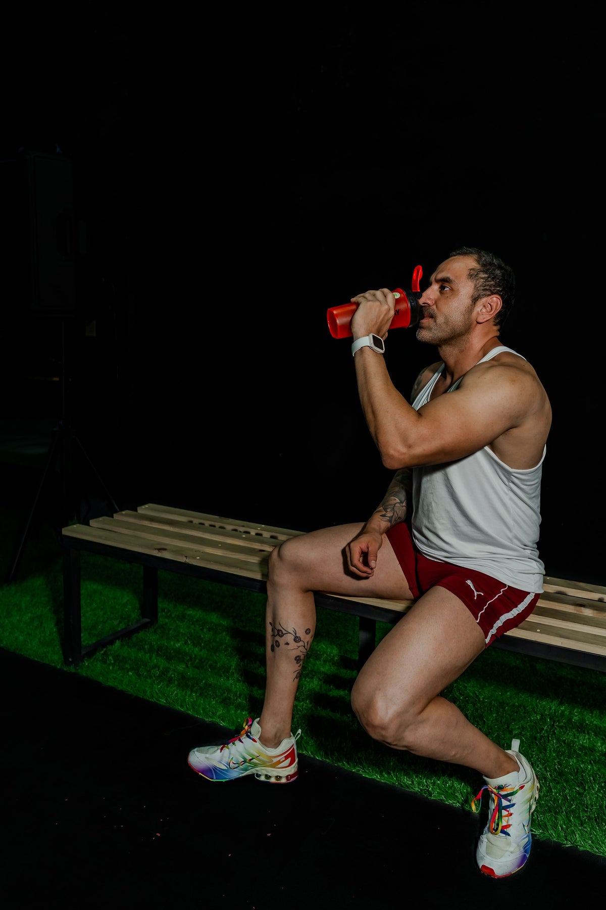 Athlete drinking from a shaker in a dark gym