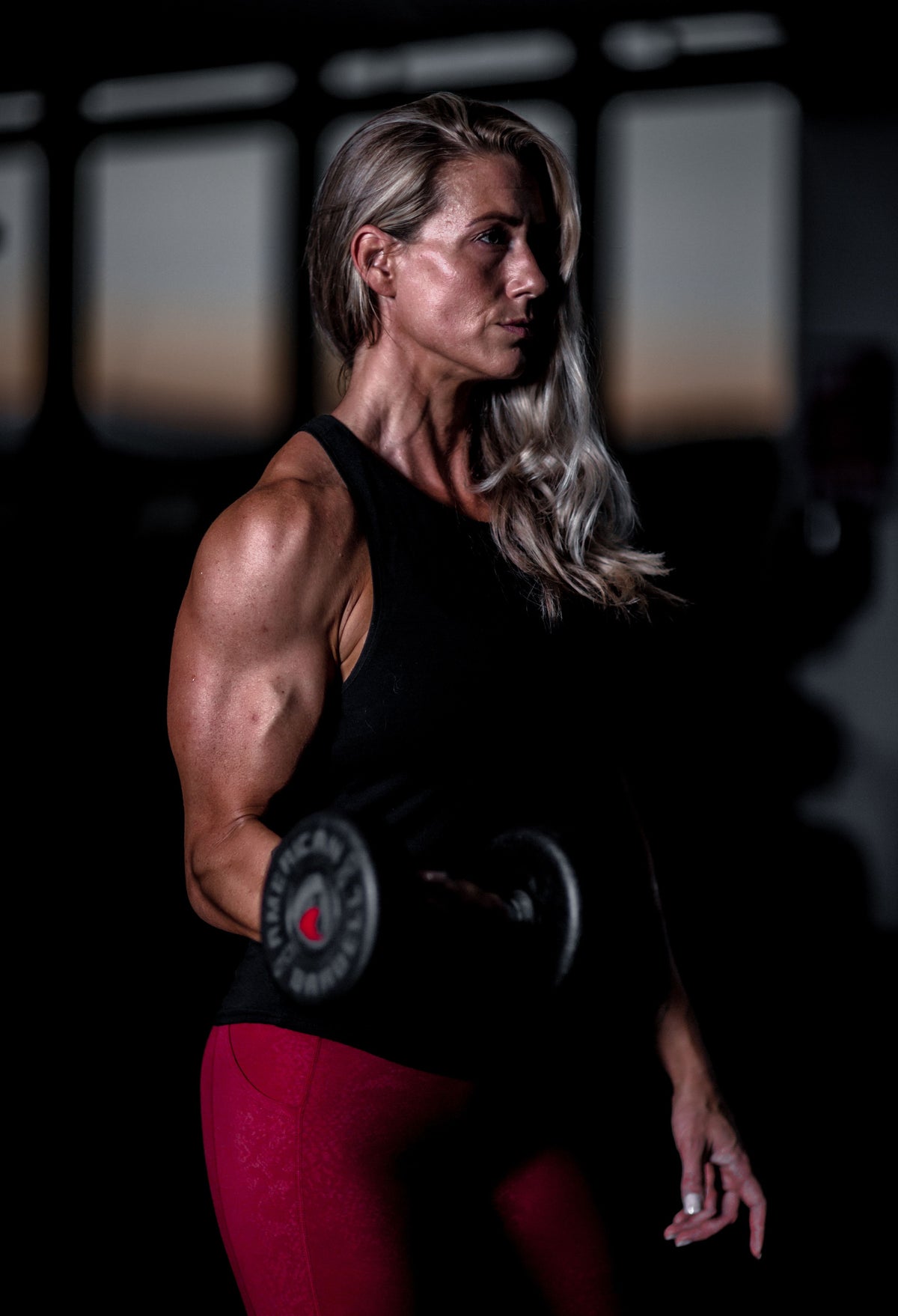Woman lifting a dumbbell in a dark gym